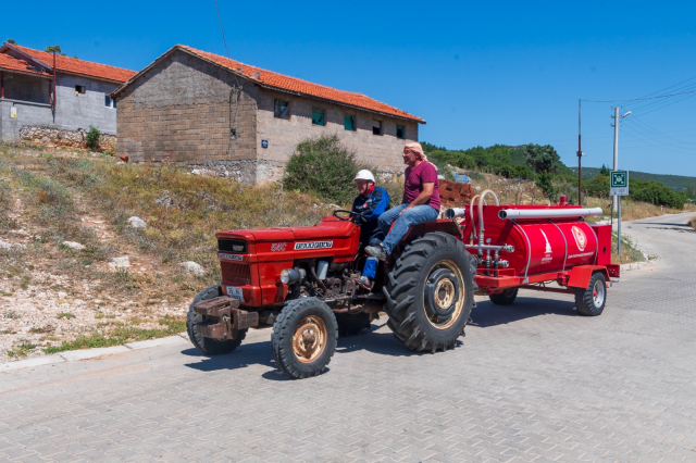 İzmir'in sıradışı çifti  

Hayatı paylaşan Sevil ve Kemal Duman çifti yangınlara da birlikte müdahale ediyor


İzmir’de yaşayan Sevil ve Kemal Duman, Urla’da yangınlara da birlikte müdahale ediyor. Duman çifti, İzmir Büyükşehir Belediyesi’nin “Yangına Dirençli Köyler” projesi kapsamında eğitim aldıktan sonra İzmir İtfaiyesi Gönüllüsü oldu. Yangın ihbarı aldıktan sonra biri motosikleti, diğeri de su tankerinin bağlı olduğu traktörü alarak olay yerine giden Duman çifti, itfaiye ekipleri gelene kadar birçok yangını başlangıç aşamasında söndürdü.


İzmir Büyükşehir Belediyesi'nin yangınlarla mücadelesine yurttaşlar da gönüllü destek veriyor. Yangına Dirençli Köyler projesi kapsamında yangına ilk müdahale için su tankeri kullanma eğitimi alan köy sakinleri, İzmir İtfaiyesi Gönüllüsü oluyor. Urla'nın Birgi Mahallesi’nde projeye destek veren gönüllüler yangınlara müdahale ederek büyük felaketleri önlüyor. Hayatı her alanda paylaşan Birgi Mahalle Muhtarı Sevil Duman ile eşi Kemal Duman,  mahalle sakini Savaş Berk ve eşi Gülin Berk o isimlerden bazıları. Sevil Duman, yangın ihbarını alan ilk isim. İhbarı aldıktan sonra eşi Kemal Duman’a ve İzmir İtfaiyesi’ne haber veren Sevil Duman hemen ardından motosikletine atlayıp olay yerine gidiyor. Eşi Kemal Duman da yangına hızlı müdahale için traktöre takılı hazır olarak beklettiği su tankeriyle ona eşlik ediyor.  O sırada Savaş Berk ve eşi Gülin Berk’e de haber veriliyor ve yangın bölgesine gelmesi sağlanıyor.