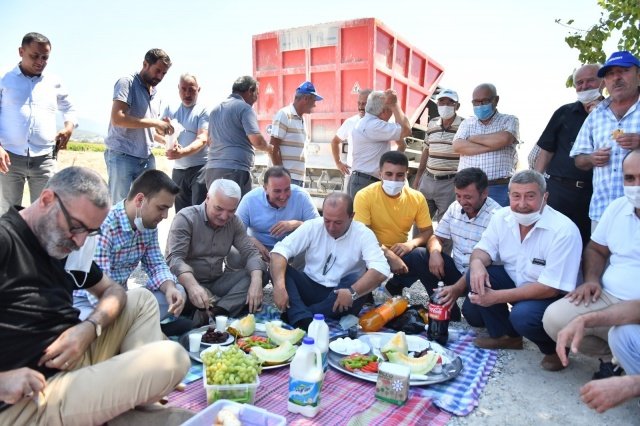 Araziye gelişinde iş makinesinin camından vatandaşları selamlayan Bilgin, çalışmaları yerinde inceledikten sonra yer sofrasına oturarak vatandaşlarla birlikte yemek yedi.