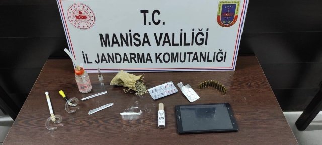 Alaşehir İlçesi Yeşilyurt Mahallesinde 24.06.2021 Günü Saat:03.10 sıralarında Alaşehir İlçe Jandarma Komutanlığınca yapılan istihbarı çalışma sonucunda Adli Mercilerden alınan arama kararına istinaden M.A(Erkek 1990 d.lu) isimli şahsın evinde yapılan aramada; -Bonzai olduğu değerlendirilen 35 gr uyuşturucu madde -1.5gr kristal uyuşturucu madde -7 adet regapen hap -6 adet Ativan hap, -12 adet 9 mm fişek -3 adet uyuşturucu içme aparatı ele geçirilmiştir. Şüpheli M.A(Erkek 1990 d.lu)  24.06.2021 günü Alaşehir Cumhuriyet Başsavcılığına sevk edilecektir.
