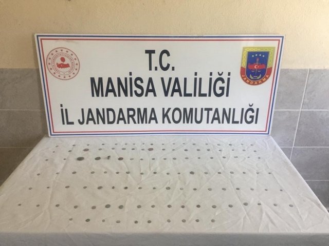 Manisa İli Ahmetli İlçesi Güldede Mahallesinde; 27.04.2022 günü saat:14.30 sıralarında Manisa İl Jandarma Komutanlığı Kaçakçılık ve Organize Suçlarla Mücadele  Şube Müdürlüğü, İstihbarat Şube Müdürlüğü ve Ahmetli İlçe Jandarma Komutanlığı ekiplerince yapılan istihbari çalışmalar neticesinde, Şüpheli M.A. (Erkek 23 yaşında) isimli şahsın sikke ve çeşitli objelerden oluşan antik dönemlere ait tarihi eserleri yurt içinde toplayıcı adı altında topladığı, toplamış olduğu eserleri  yurtdışına satış yapmak amacıyla internet siteleri ve sosyal paylaşım sitelerinde müşteri arayışına girdiği tespit edilmiştir.
Adli makamlardan  alınan  arama kararına istinaden;
Şüphelinin yakalanmamak İçin binmiş olduğu ticari takside yapılan aramada çeşitli Antik dönemlere ait (Roma, Bizans, Helenistik) olduğu değerlendirilen sikke,objelerin bulunduğu toplam (119) adet  eser ele geçirilmiştir. Ele geçirilen tarihi sikke ve objeler  Manisa İl Müze Müdürlüğü ekiplerine teslim edilecektir. Şüpheli M.A. gözaltına alınmıştır. 28.04.2022 tarihinde Adli makamlara sevk edilecektir.