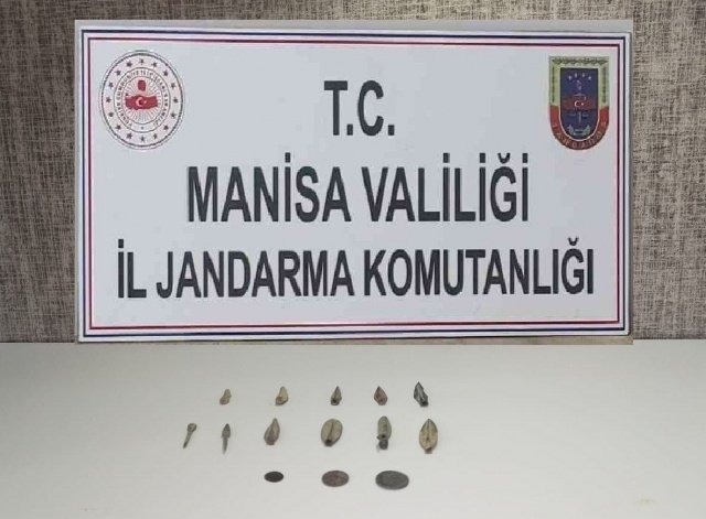 Manisa ili Şehzadeler ilçesi Kuşlubahçe Mahallesi (Emniyet Bölgesi) ve Yunusemre ilçesi Uncubozköy Mahallesi  (Emniyet Bölgesi) ile Saruhanlı ilçesi Gökçeköy Mahallelerinde ikamet eden şüpheliler H.U(1987/E) ile A.A(1961/E)'nın tarihi eser niteliğindeki sikke ve objeler bulundurdukları yapılan istihbari çalışmalar neticesinde tespit edilmiştir.

Manisa İl Jandarma Komutanlığı İsth. ve KOM Şube Müdürlüğü ile Şehzadeler İlçe J.K.lığınca Müşterek olarak Adli merciden alınan Arama Kararı gereğince; 23.02.2021 günü Saat:07.00 itibariyle yapılan aramalarda;

Tunç Çağına (M.Ö 1000 yılları) ait olduğu değerlendirilen
(11) Adet Mızrak Ucu,
Roma Dönemine ait olduğu değerlendirilen (3) Adet Bronz Sikke ele geçirilmiştir.

Şüpheli şahıslar ifadeleri alınmasına müteakip serbest bırakılmıştır.